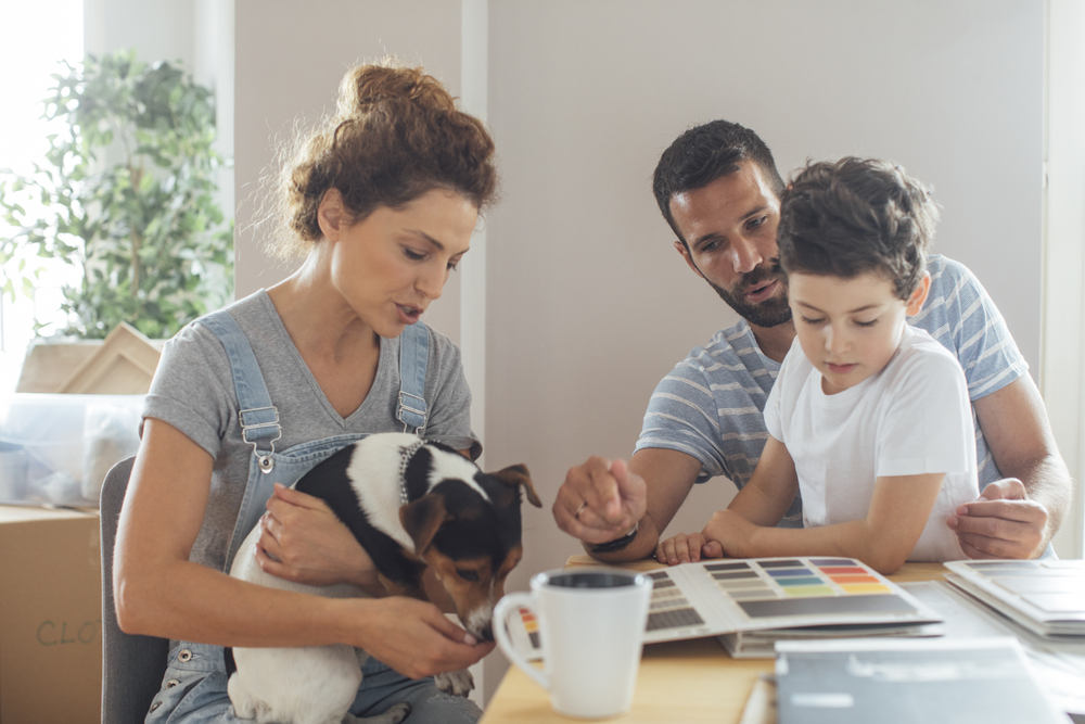 A family of three sitting at the table with their dog